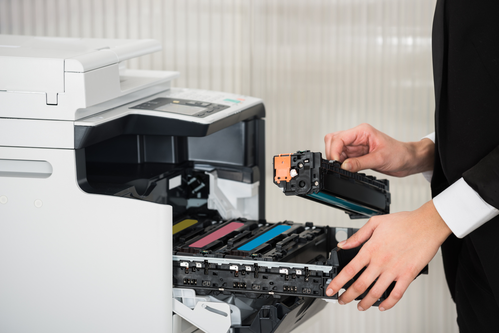Žena v kanceláří vyměňující toner ve velké laserové tiskárně.